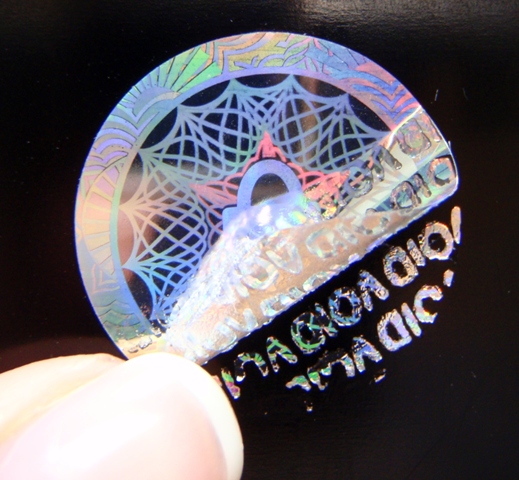 Rundes Hologramm-Siegel mit VOID Sicherheitseffekt, der bei unerlaubten Ablöseversuchen ausgelöst wird