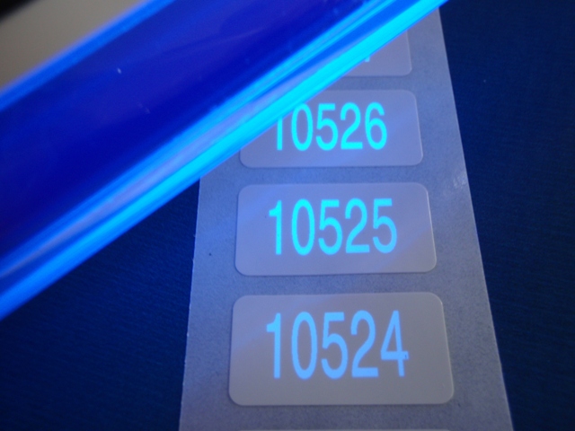 Lumineszenz-Sicherheitsnummerierung auf weißer PE-Folie, die unter UV-Licht sichtbar gemacht wird