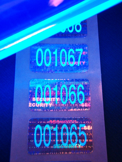 Hologrammetiketten mit Nummerierung, die erst unter speziellem UV-Licht sichtbar wird