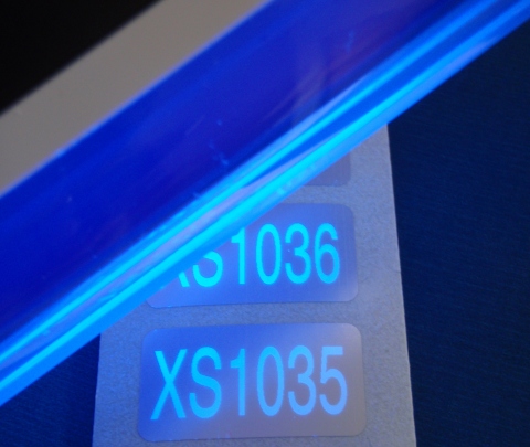 Sicherheits-Nummerierung wird mit blauem UV-Licht sichtbar gemacht Silberne Polyesteraufkleber, die mit Spezialdruckfarbe nummeriert und nur unter blauem UV-Licht lesbar sind
